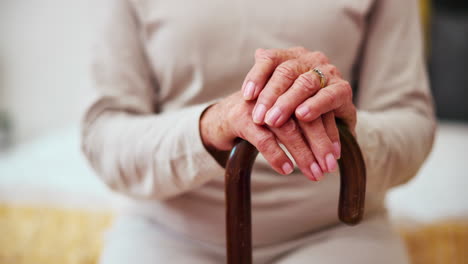 cane, hands and senior woman in home in bedroom