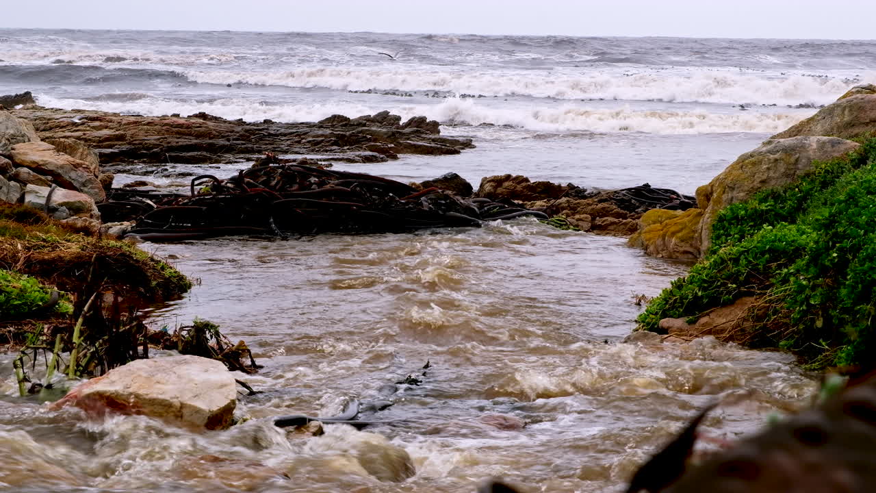 el agua de lluvia turbia desemboca en el mar agitado en la costa desde el sistema de drenaje, telefoto