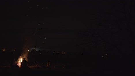 2 men by a big sparkling campfire dark night 4k