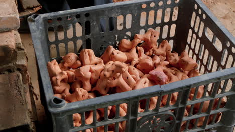 slight high angle hand places clay animal figurines into crate, than ha hoi an vietnam