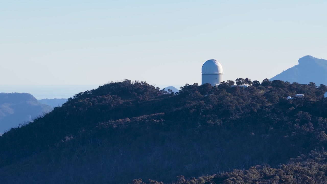 Ampia inquadratura di una cupola di osservatorio astronomico su una cresta montuosa boscosa in Australia