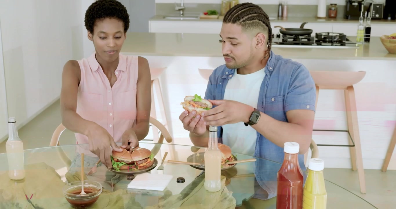 Deux amis levant des bouteilles, montrant une superposition de sauce en filet, préparant des burgers pour du marketing alimentaire.