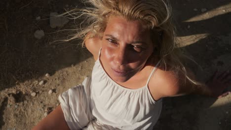 a woman in a white dress screams out in frustration and sorrow as she sits alone outside in the dry desert sand