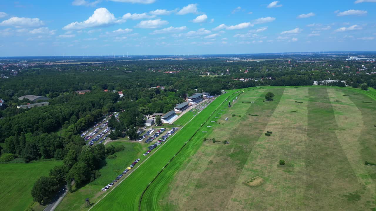 Jockeys on racehorses on horse racing track, showcasing the vibrant green turf, stands filled with spectator landscape beyond. Stunning aerial view flight fly reverse drone
