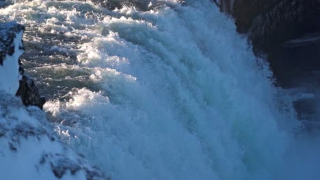 iceland's iconic goðafoss, the "waterfall of the gods," roars powerfully through a serene winter landscape, its cascading waters framed by snow-covered cliffs and icy formations