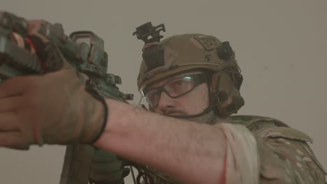 serious armed soldier standing in building and taking aim