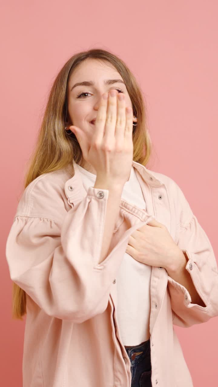 Young woman showing love and affection on pink background