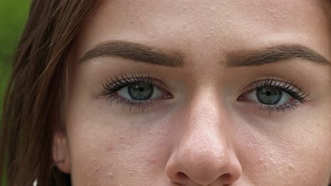 primer plano extremo de los ojos verdes de una modelo morena parpadeando a cámara lenta