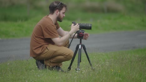 videographer on location prepares his camera and tripod equipment to shoot