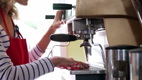 waitress wiping espresso machine with napkin in cafã©