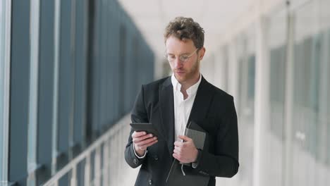 nice-businessman-walks-down-the-hall-with-a-tablet