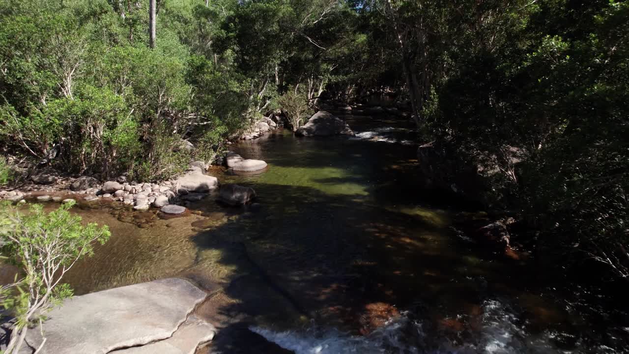un dron disparado hacia atrás en el río murray falls en queensland, australia, en un día soleado.