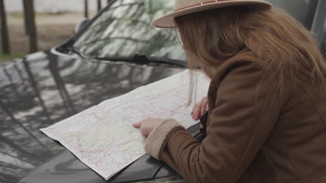 fille aux cheveux rouges a perdu sa voiture au milieu de la campagne et utilise une carte pour retrouver son chemin