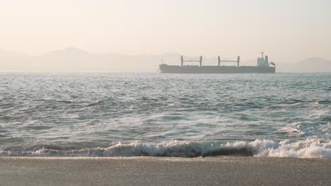 oil rig on the horizon in the rough seas seen from the coast at dawn