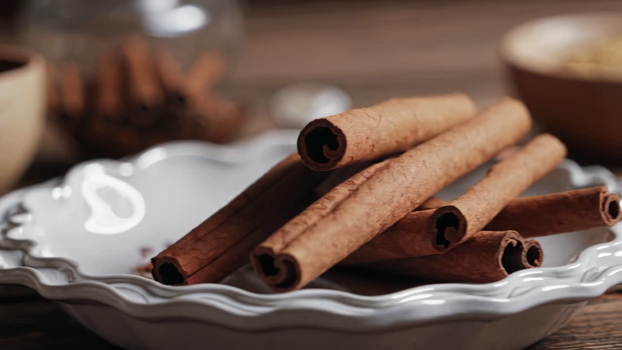 Vídeo em close-up de paus de canela em um prato decorativo, filmado de um ângulo baixo, destacando a textura