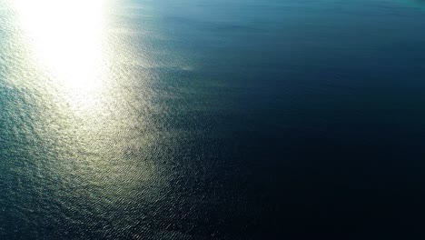 aerial panoramic overview of deep blue water and bright plume of warm sunlight on ocean shimmering