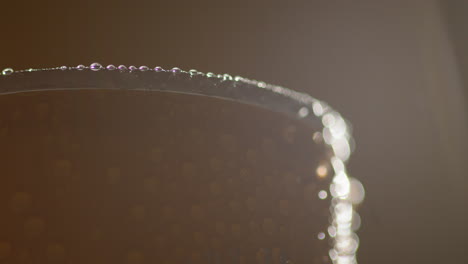 close up backlit shot of condensation droplets on revolving takeaway can of cold beer or soft drink