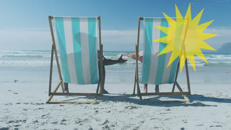 animation of sun over senior african american couple lying on sunbeds on sunny beach