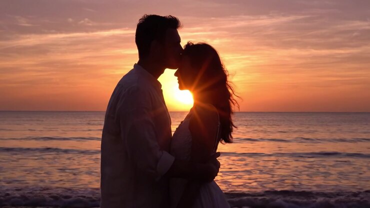 Silhouette romantica di una coppia che si abbraccia al tramonto su una spiaggia serena, catturando l'essenza dell'amore e della connessione contro un orizzonte mozzafiato