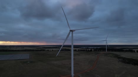 eolic wind turbines with blades rotating in rural landscape with cloudy sky