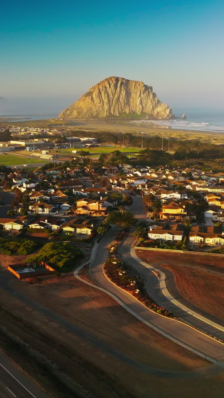 Picturesque seaside city of Morro Bay on the shore of the Pacific. Beautiful sunny day scenery from aerial perspective. Hazy horizon at backdrop. Vertical video