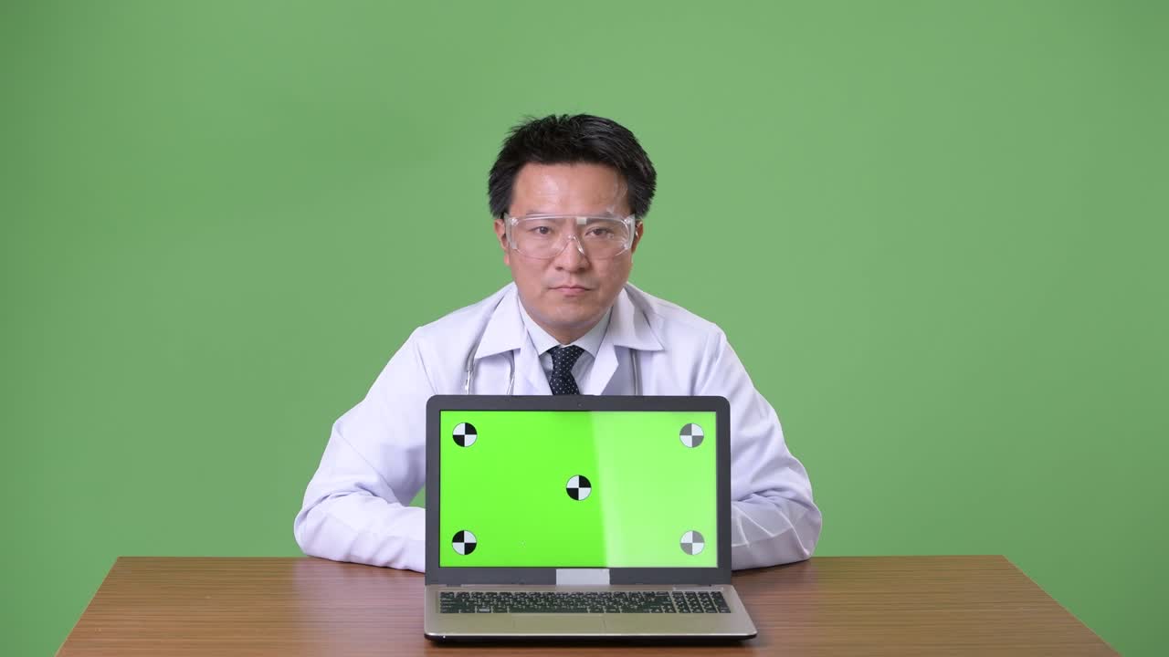 성숙한 일본인 남성, 초록색 배경의 의사