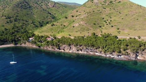 A-stunning-aerial-view-of-a-drone-orbiting-a-wooden-sailboat-anchored-in-a-beautiful-bay