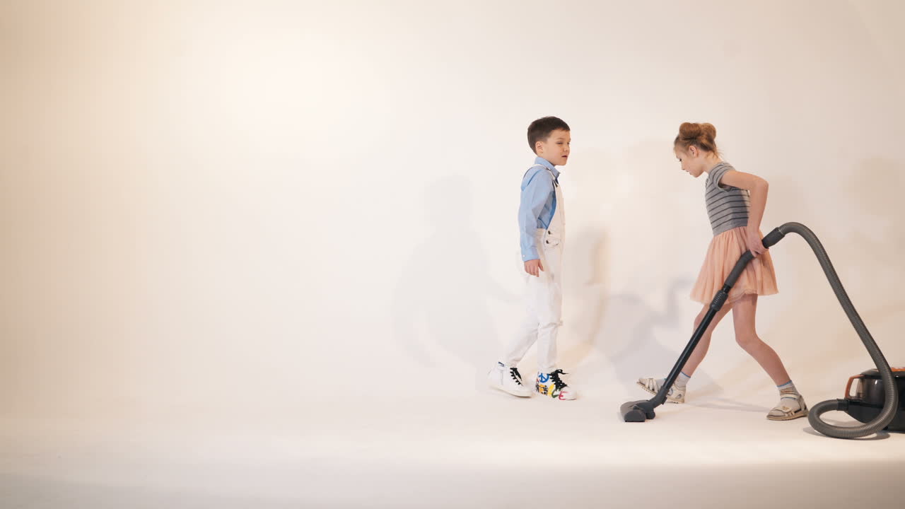 Little children play with a vacuum cleaner. Emotions of the child. Studio shooting of children.