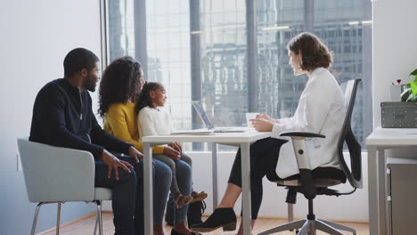 family having consultation with female pediatrician in hospital office