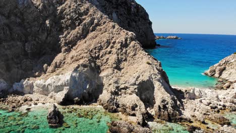 playa de agia eleni con aguas turquesas y acantilados rocosos - retroceso aéreo