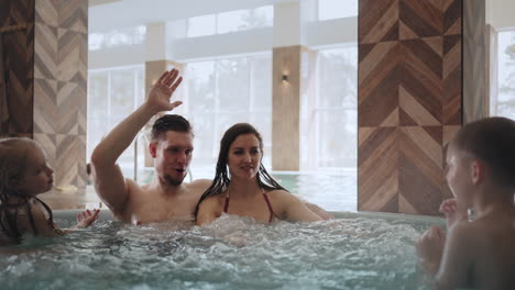 family-with-kids-is-resting-in-thermal-bath-of-modern-wellness-center-children-and-parents-are-relaxing-in-jacuzzi