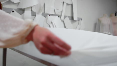 clothing designer is working with measurements on a studio table. shot on in 4k uhd . closeup deploy a skein of white fabric in white and light-colored sewing in slow motion.