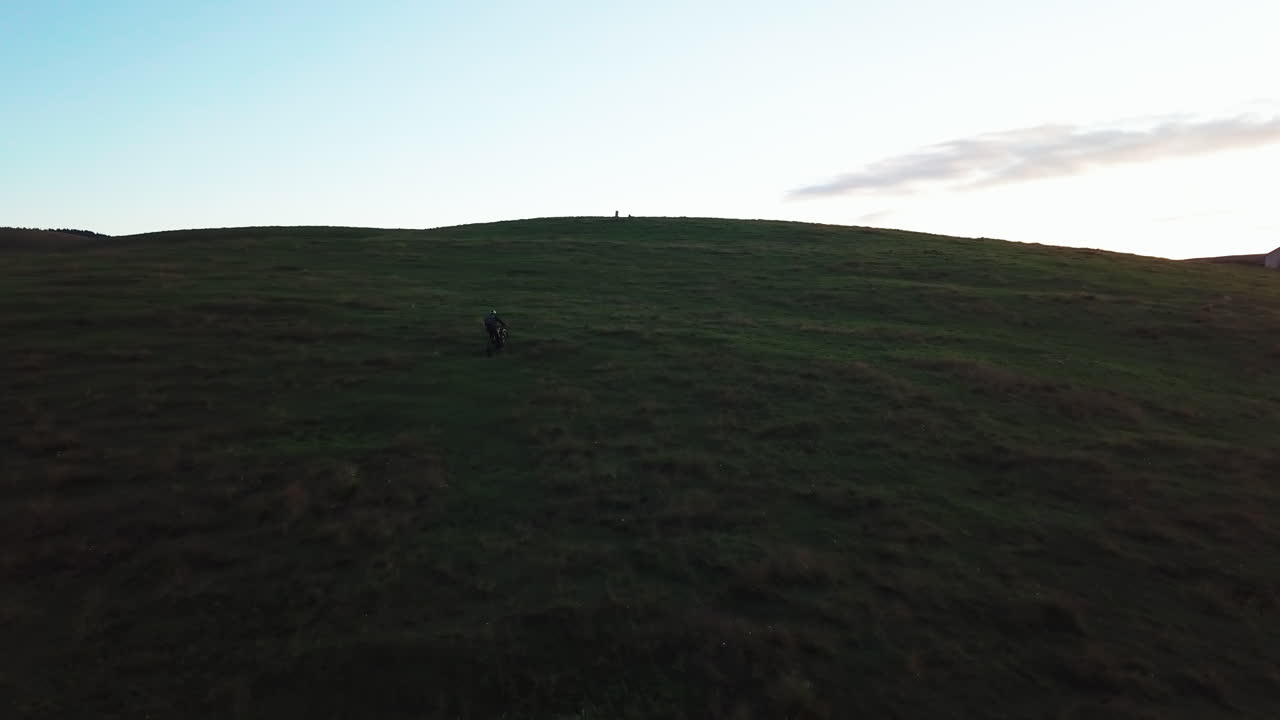 Mountain Biker at Sunset on a Grassy Hill