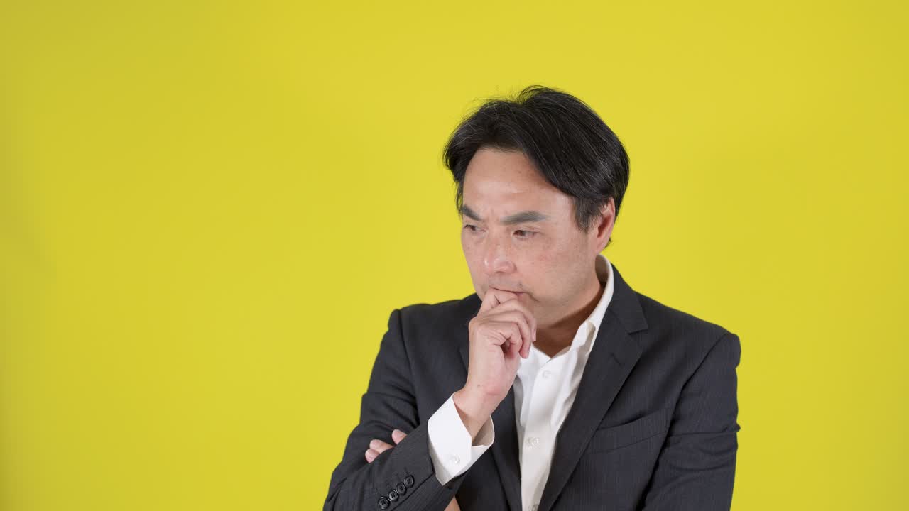スーツを着た男性が考え、上を指し、そして喜びに満ちた表情でアイデアを祝福する、スタジオ照明。