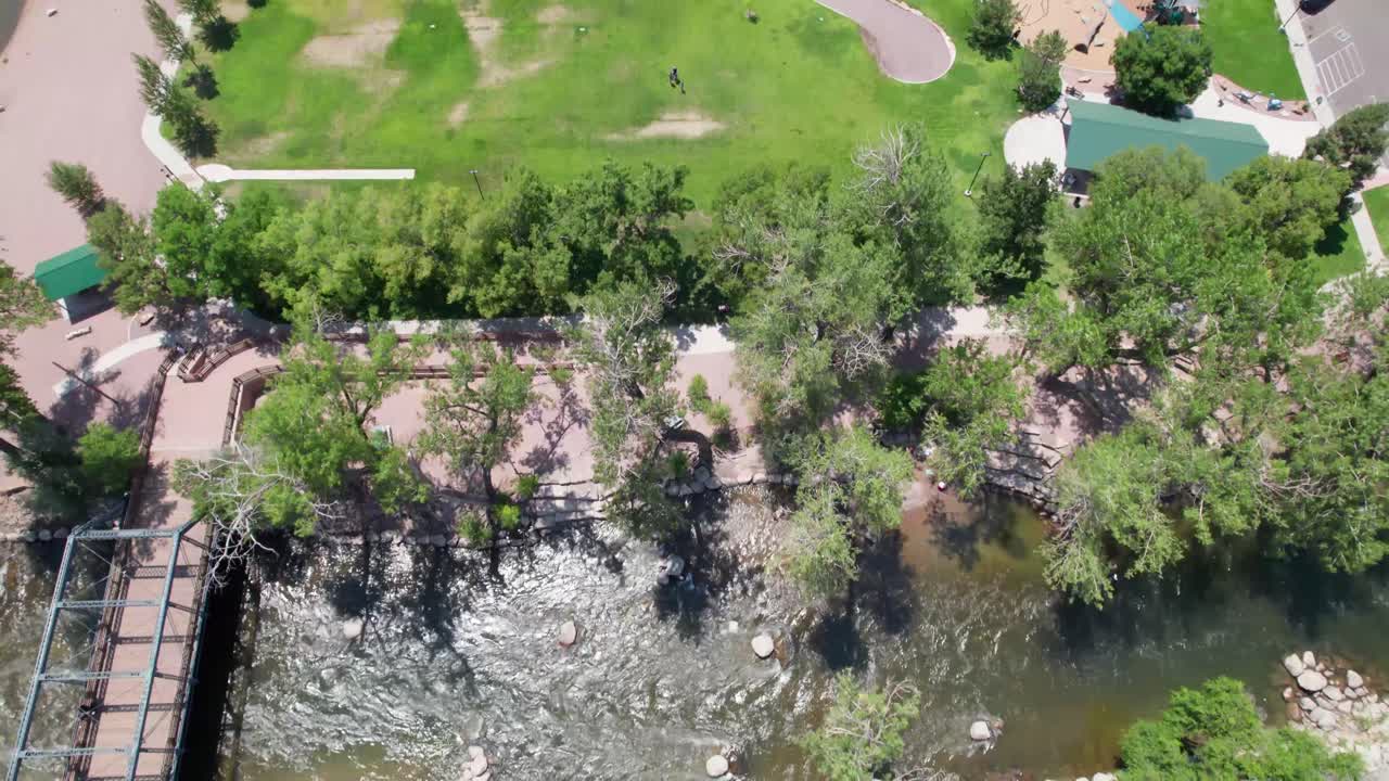 Aerial video of the Arkansas River in Canon City, Colorado. Camera is looking straight down and flies over a parking lot and the river. A bridge can be seen to the left side of the video