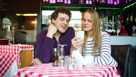 Una-Pareja-Joven-En-Una-Cafetería-Teniendo-Un-Video-Chat-En-Un-Teléfono-Inteligente