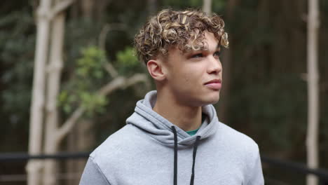 young man in gray hoodie enjoying nature, looking thoughtful in forest