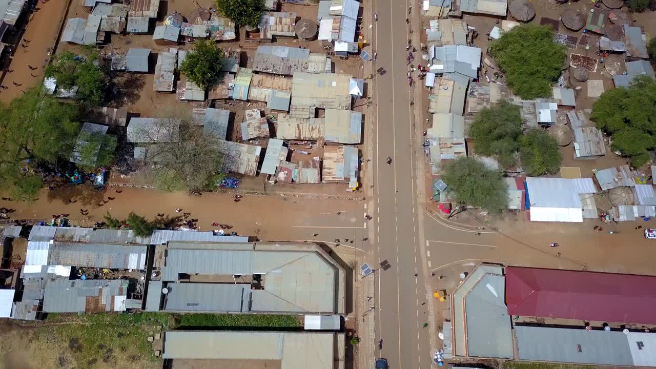 Aerial view capturing a motorcycle navigating through Moroto Town, highlighting the vibrant urban life and infrastructure of Uganda's Karamoja region, top down flying over and reveal drone shot