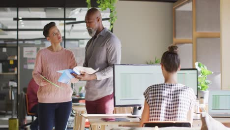 Happy-diverse-business-people-holding-documents-and-discussing-work-at-office