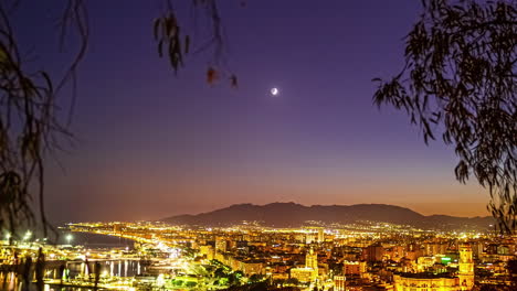 Time-lapse-of-the-sun-setting-over-Malaga,-Spain-with-trees-framing-the-shot