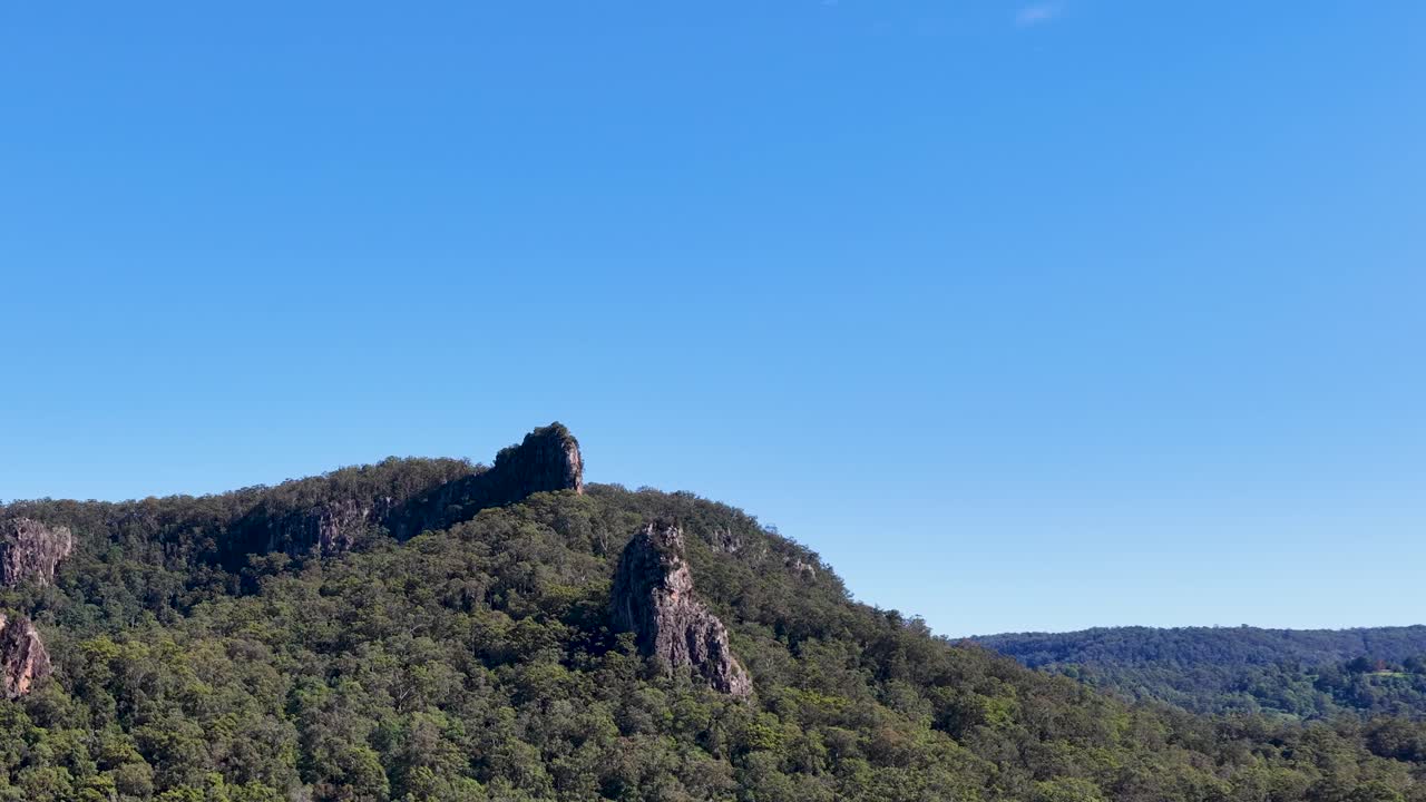 A serene landscape of Nimbin Rocks under clear blue skies, showcasing lush greenery and natural rock formations