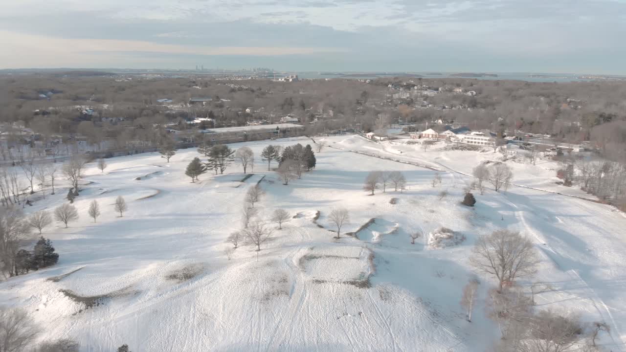 Panorointi vasemmalle lumisen golfkentän yli paljastaen Bostonin, MA, USA horisontissa.
