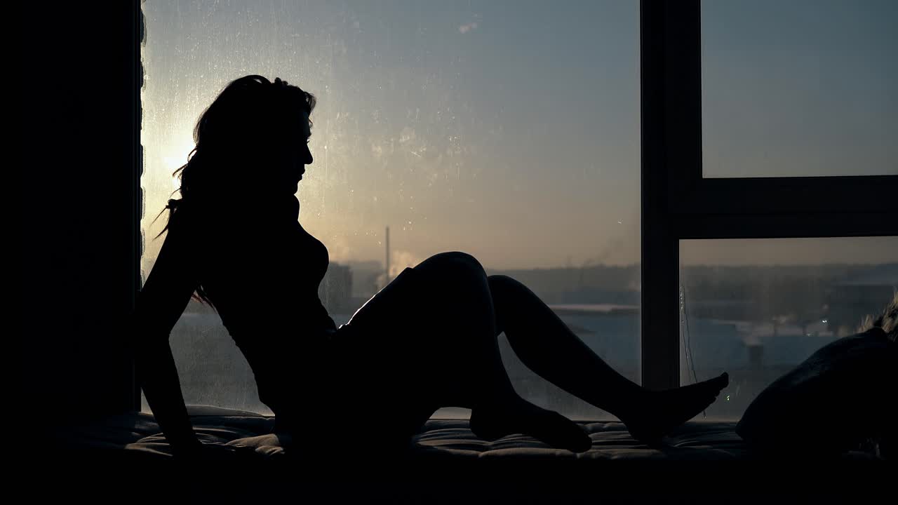 우아한 여성은 창문 근처의 휴식 장소에서 편안하게됩니다.