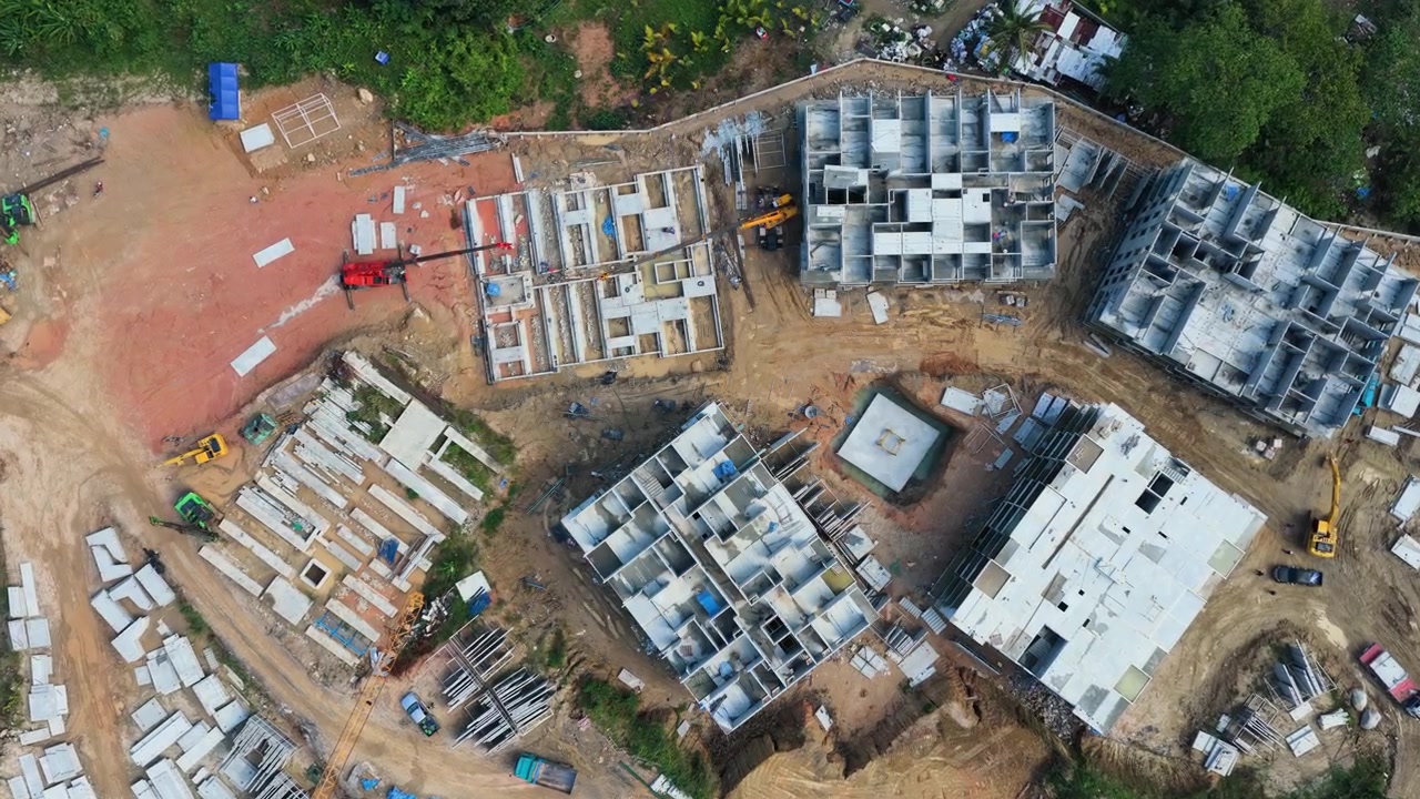 Vista aérea superior de canteiro de obras ativo de resort em Phuket com edifícios de concreto, drone desce para padrões geométricos na parede