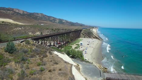 A-beautiful-aerial-over-a-train-crossing-a-bridge-along-the-Pacific-Ocean