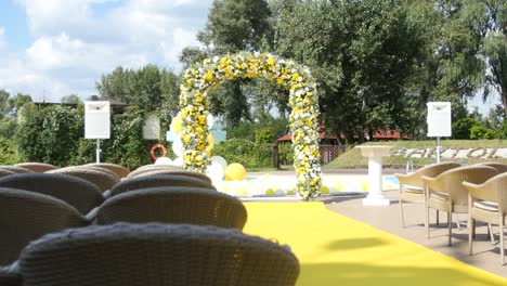 outdoor wedding ceremony with flower arch and yellow decorations