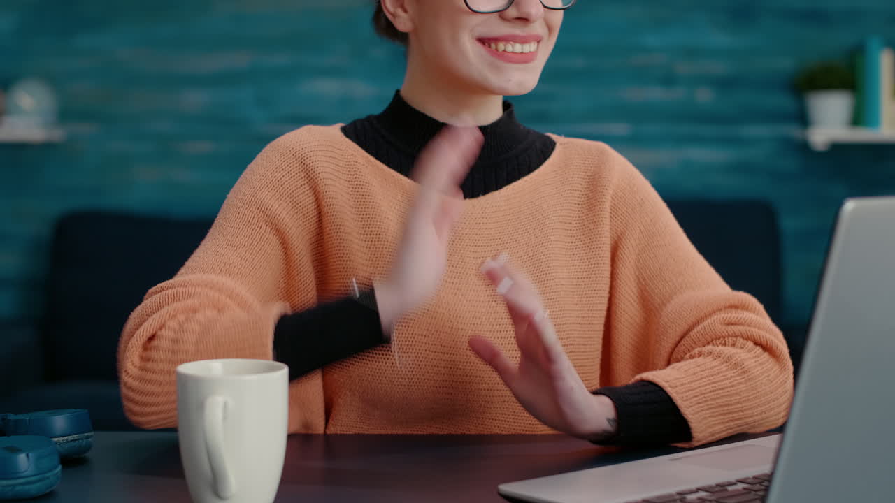 Studentessa che saluta con la mano durante una videochiamata sul portatile