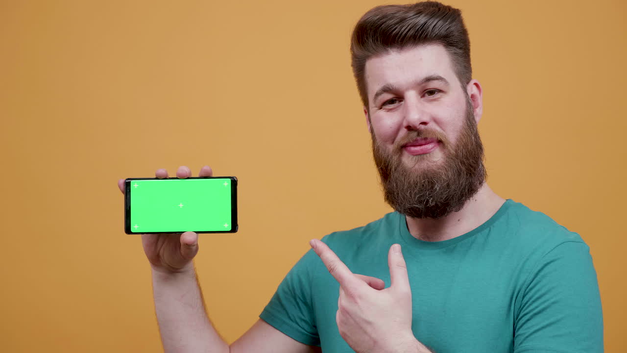 초록색 화면 을 가진 스마트폰 을 들고 있는 남자