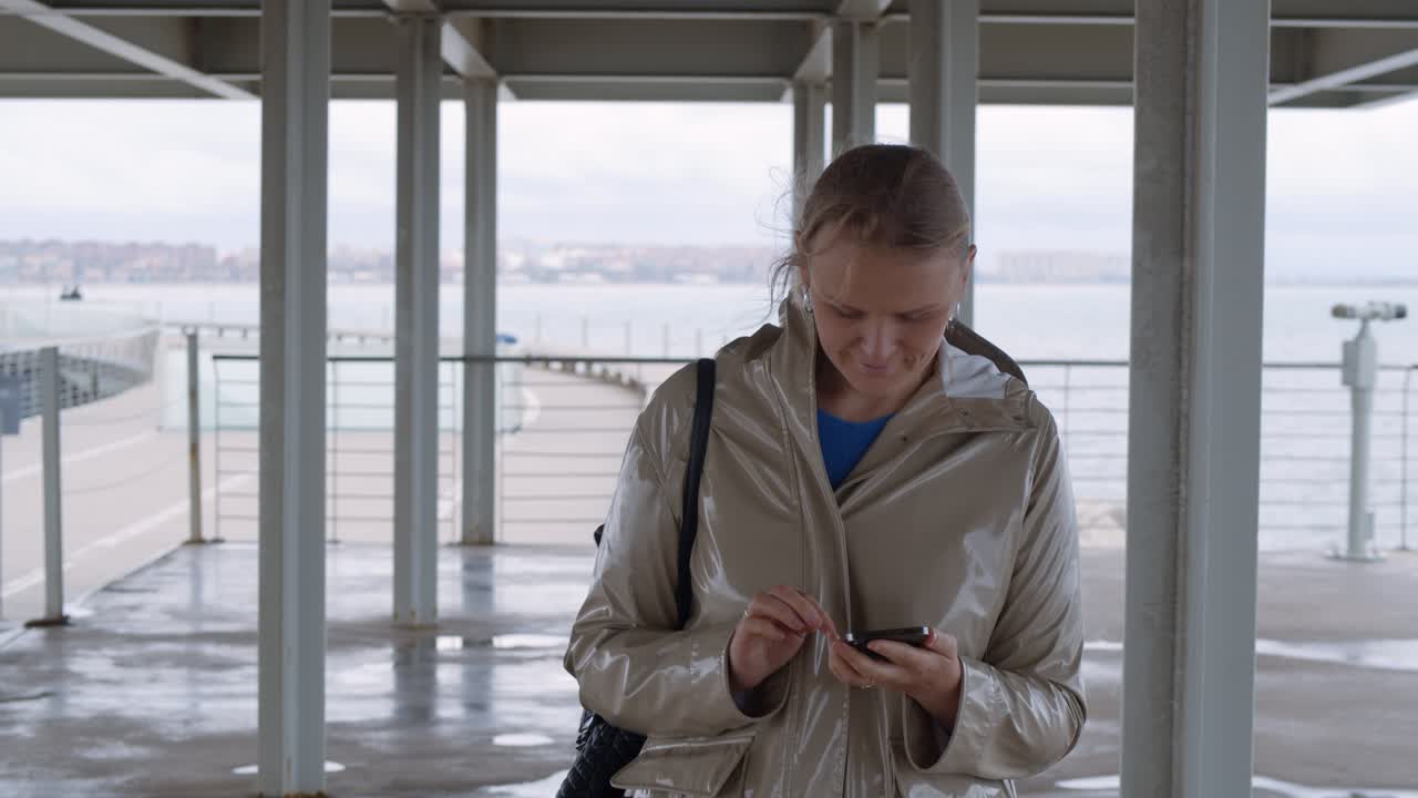 Woman surfing net while walking on waterfront