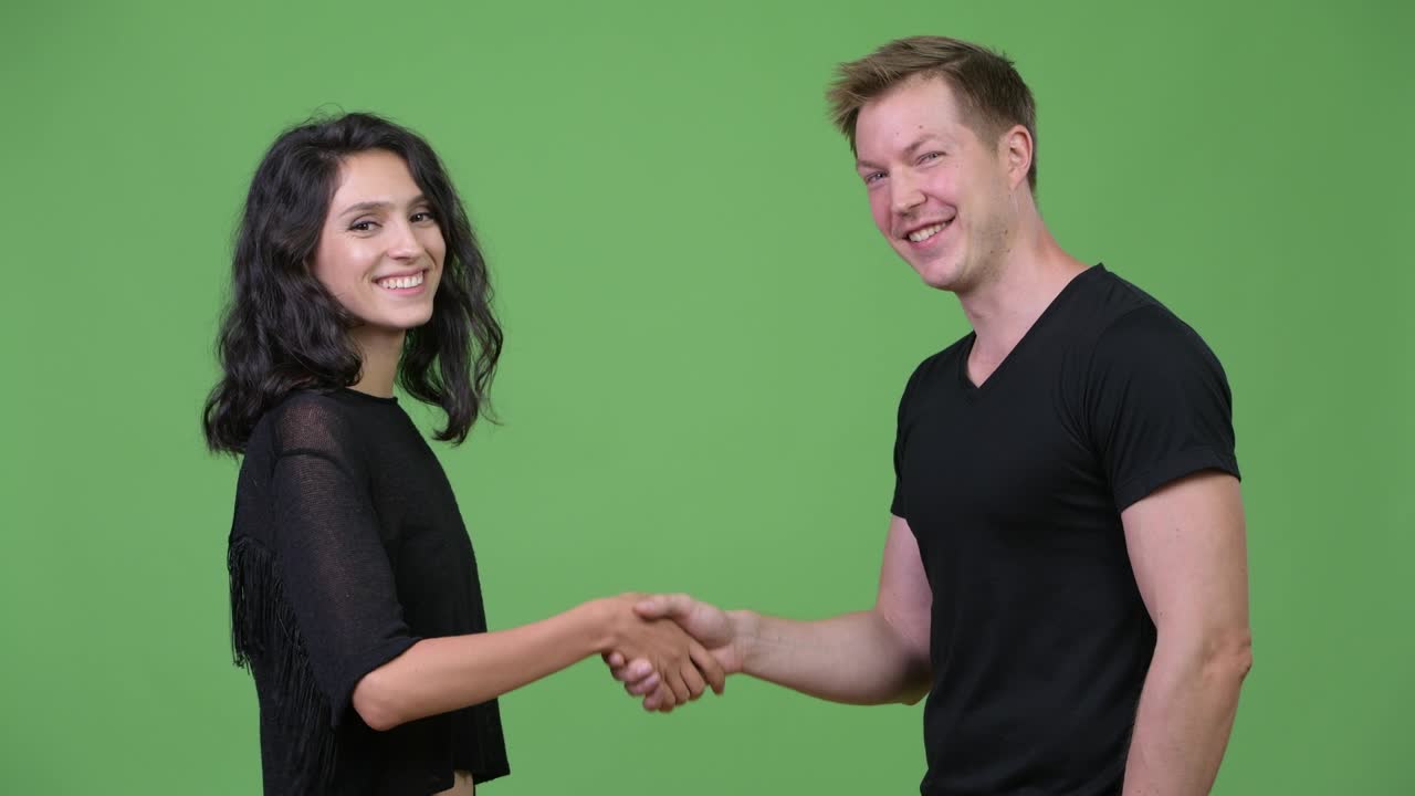 fotografía de estudio de una pareja joven y feliz estrechando la mano